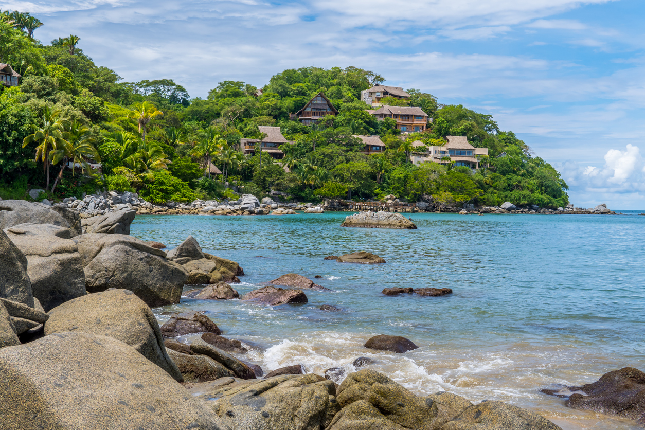 Rocky shore with blue waters at Playa de los Muertos beach at Sayulita, Nayarit, Mexico
